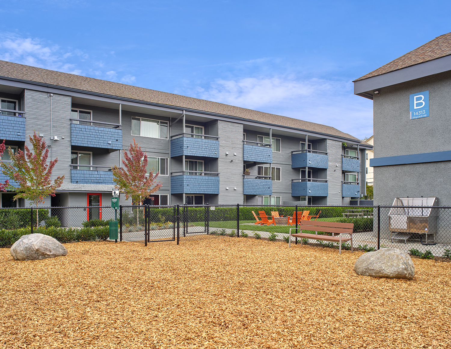 Dog run with enclosed fence outside exterior of building. Wood chips fill the dog area. at 3030 Lake City, Seattle, Washington